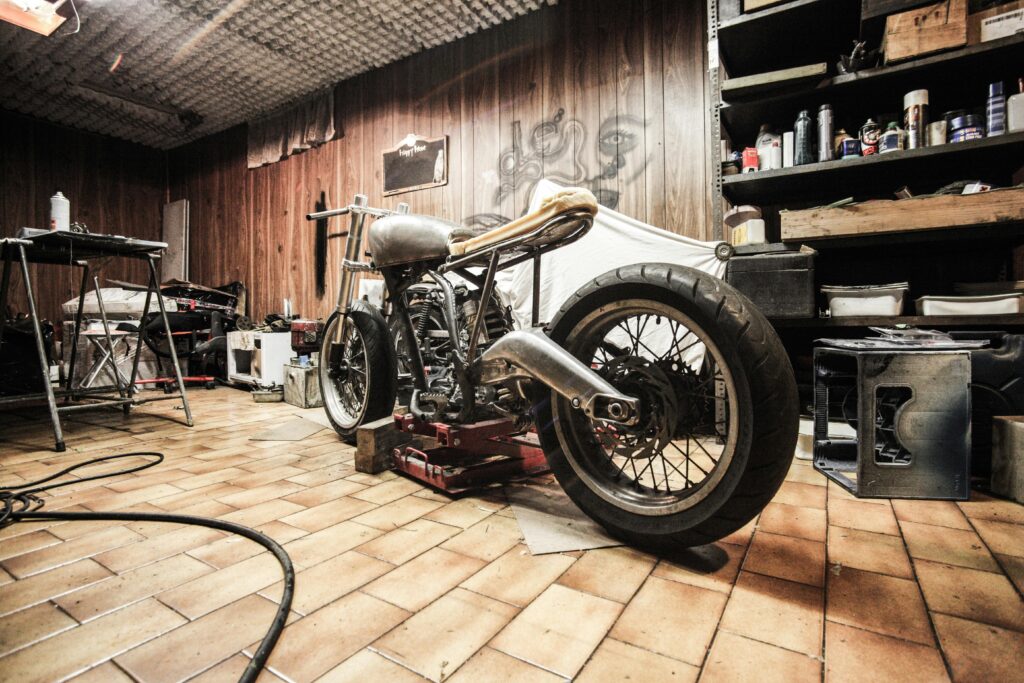 A vintage motorcycle under repair in a cluttered workshop, showcasing DIY craftsmanship.